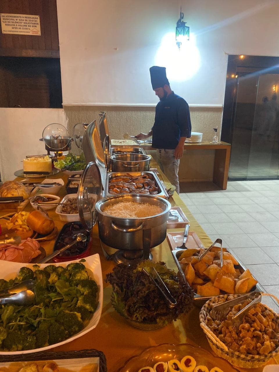 Chef Sérgio Brito finalizando pratos sobre a bancada do buffet durante um evento
