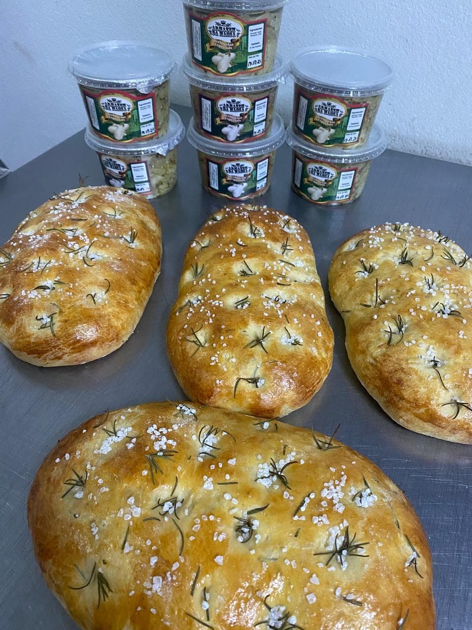 Focaccias de alecrim ao lado de potes de molho e antepasto do Armazém das Massas